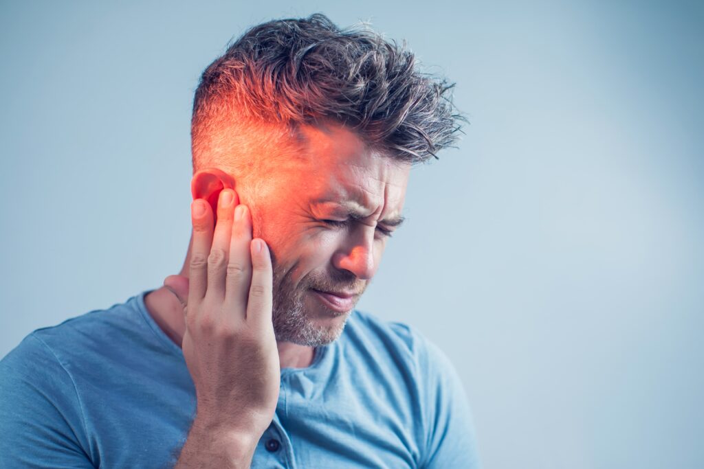 Man touching his ear, appearing to experience ear pain.